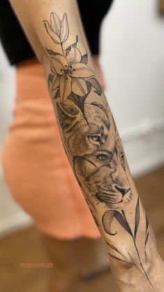 a woman with a tattoo on her arm holding onto a cat and lily flower bouquet