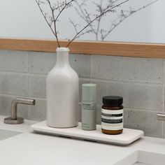 a white bottle and some medicine bottles on a counter in front of a sink with a mirror