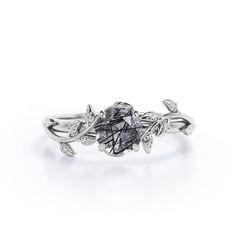 a white gold ring with a black diamond in the center and leaves on each side