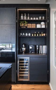 a kitchen with black cupboards and shelves filled with dishes, coffee maker and other items