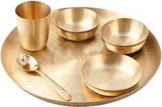 a gold plate with four bowls and two spoons