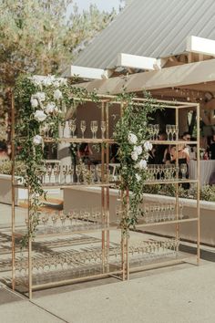 an outdoor bar set up with wine glasses and greenery