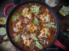 a pan filled with eggs and vegetables on top of a table next to sliced avocados