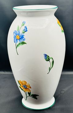 a white vase with blue and yellow flowers painted on it