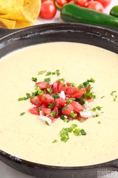 a bowl of dip with tomatoes and cilantro garnish on the side