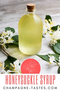 a bottle of honeysuckle syrup sitting on top of a table with flowers around it