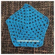 a blue crocheted square on top of a brown cloth