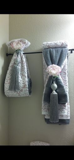 two towels hanging on a clothes line with flowers in the middle and one holding a flower