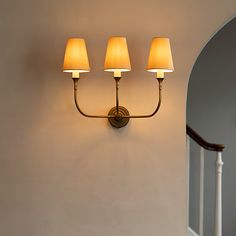 three lamps are on the wall next to a banister and stair case in an entryway