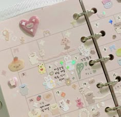 a pink planner with stickers on it is open to show the pages and numbers