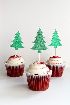 three cupcakes with frosting and trees on top