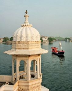 a boat is in the water next to a white building with a dome on top