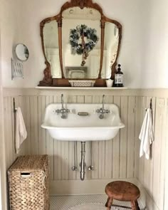 a white sink sitting under a bathroom mirror next to a wooden shelf with baskets on it