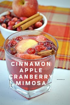 cinnamon apple cranberry mimosa in a glass with cinnamon sticks and apples