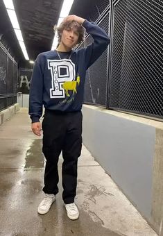 a young man is standing in the middle of a tunnel wearing a sweatshirt and sweatpants