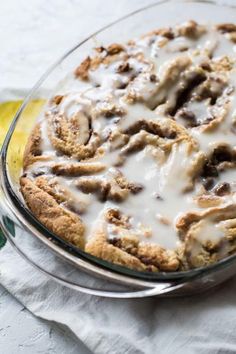 a glass dish filled with cinnamon rolls covered in icing