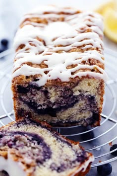 a close up of a cake on a rack with blueberries and lemons in the background