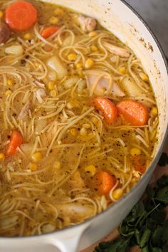 a pot filled with noodles and carrots on top of a table