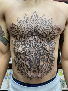 a man with tattoos on his chest wearing a headdress