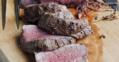 some meat is sitting on a cutting board with a knife and fork next to it