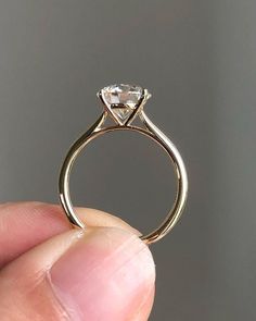 a person holding up a diamond ring in their hand