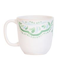 a white coffee cup with green designs on the outside and inside, sitting against a white background