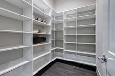 an empty walk in closet with white shelving