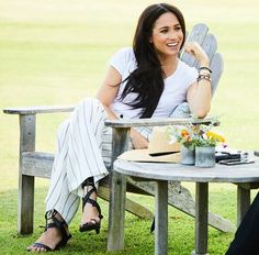 a man and woman sitting at a picnic table talking to each other while one looks on