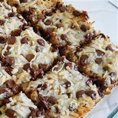 a close up of a dessert with chocolate chips and coconut on the top, in a glass dish