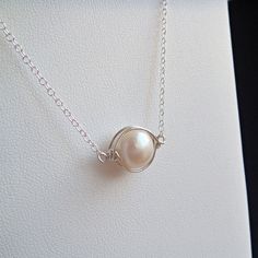 Caged Pearl Necklace- A single large pearl is wrapped in argentium sterling silver and suspended from sterling silver chain. Simple and elegant, this necklace is a unique take on classic pearls. The hand wired frame gives it a slightly organic feel and highlights the pearl wonderfully. Perfect whether for a special occasion or for wearing every day. Necklace is approximately 16 inches (40.6 cm) around, and the pearl itself is about 9 mm across. See some great coordinating earrings here: http://w Caged Pearl Necklace, Wire Wrapped Pearl Pendant, Royalcore Accessories, Elegant Silver Wire-wrapped Pearl Necklace, Classic Wire Wrapped Jewelry Gift, Elegant Wire Wrapped Pearl Necklace, Elegant Silver Wire Wrapped Pearl Necklace, Wire-wrapped Pearl Necklace For Gift, Wire Wrapped Pearl Necklace Gift