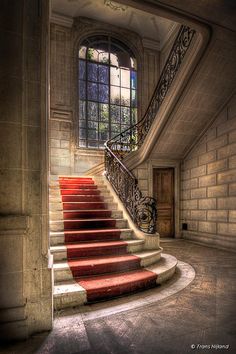 an old building with red stairs leading up to the second floor and a large window