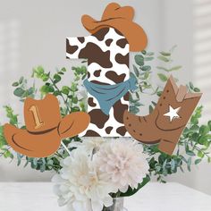 a vase filled with flowers and cutouts of cowboy hats on top of each other