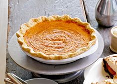 a pie sitting on top of a wooden table next to other plates and bowls filled with food