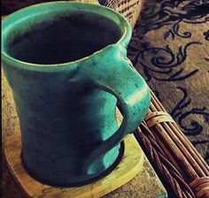 a blue coffee mug sitting on top of a wooden table next to a wicker basket