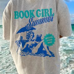 a person standing on the beach wearing a book girl t - shirt