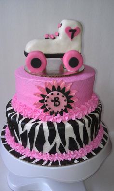 a three tiered cake decorated with zebra print and pink accents, including a baby carriage