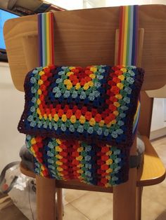 a multicolored crocheted bag sitting on top of a wooden chair