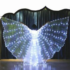 a woman is standing in front of a stage with lights on her wings