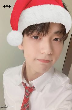 a young man wearing a red and white santa's hat with his tie on