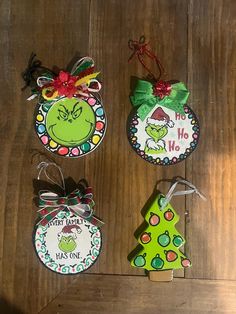 three christmas ornament hanging on a wooden floor next to each other, one with an elf's head