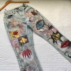 an old pair of jeans with patches on them sitting on top of a white bed