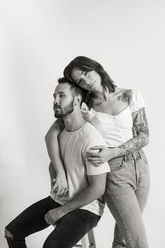 a man sitting on a stool next to a woman who is holding his arm around him