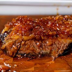 a piece of meat covered in sauce on top of a wooden cutting board