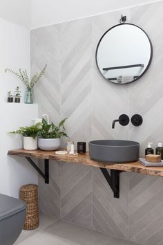 the bathroom is decorated in white and grey tones with black accents, including a round mirror