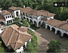 an aerial view of a large home surrounded by trees and shrubs with brown tile roofing