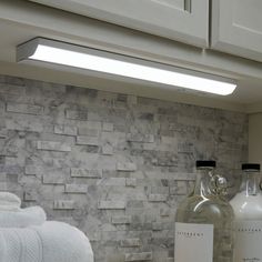 a bottle of wine sitting on top of a counter next to towels and soap dispenser