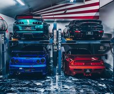 several cars are parked in a garage with an american flag on the wall behind them