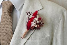 a boutonniere with feathers and flowers on the lapel of a man