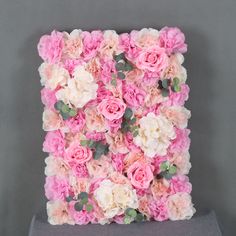 pink and white flowers are arranged in the shape of a letter on a gray surface