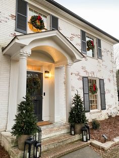 a white brick house with wreaths on the front door